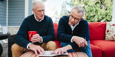 Two older men looking at a crossword puzzle together